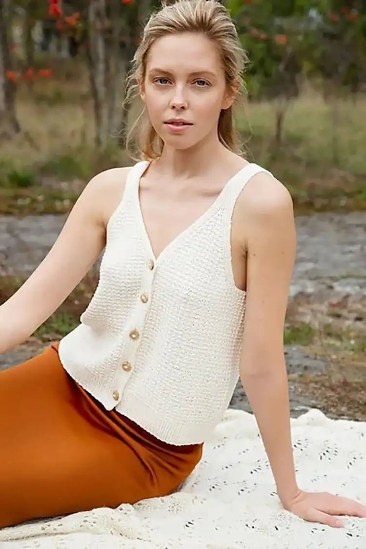 A knitted Canyon Clay Top, showcasing its symmetrical design and top-down construction, offering versatile button placement.