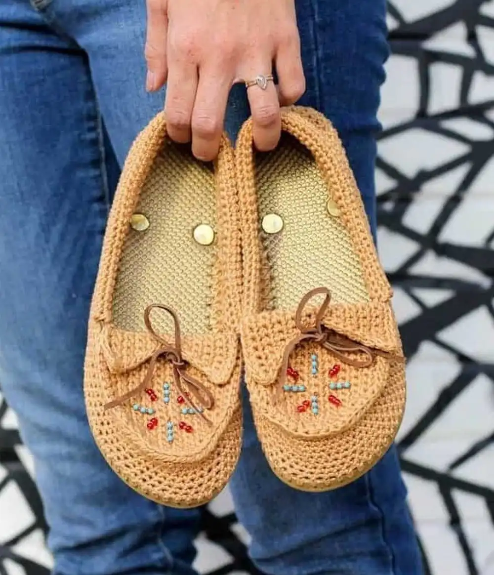 Rustic moccasin-style crochet slippers with a distinct stitched toe and fold-over cuff.