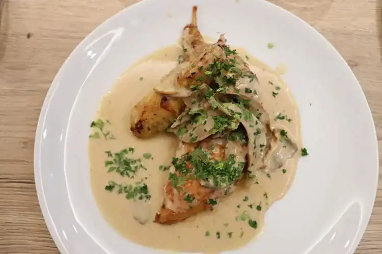 Seared pheasant in a white wine cream sauce, presented in a serving dish.