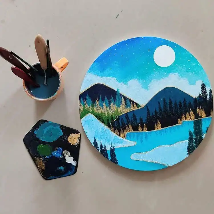 Mountains painting on a small circular canvas with metallic accents.