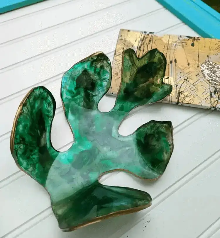 An epoxy resin geode wall mirror with shimmering gold edges, crushed glass, and layers of blue and white resin mimicking a natural geode.