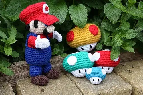 A miniature green 1Up Mushroom amigurumi from Super Mario, intricately crocheted with white spots.