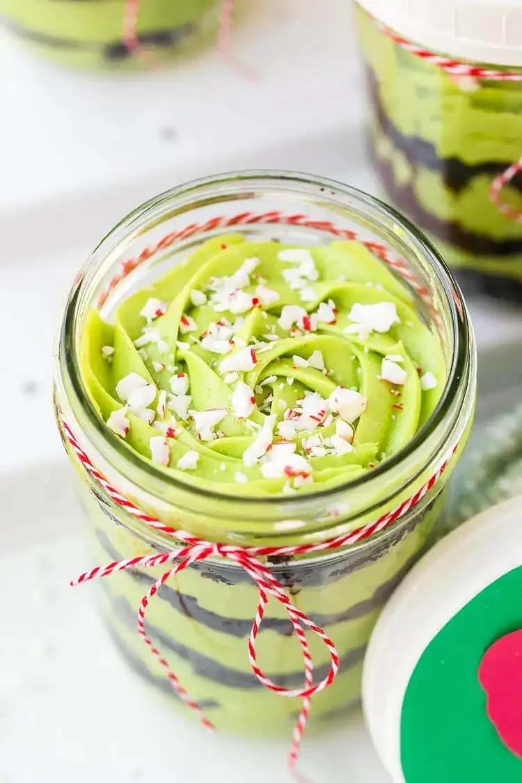 Grinch Cake in Jars with green cake layers, creamy frosting, and crushed candy canes for a festive holiday treat.