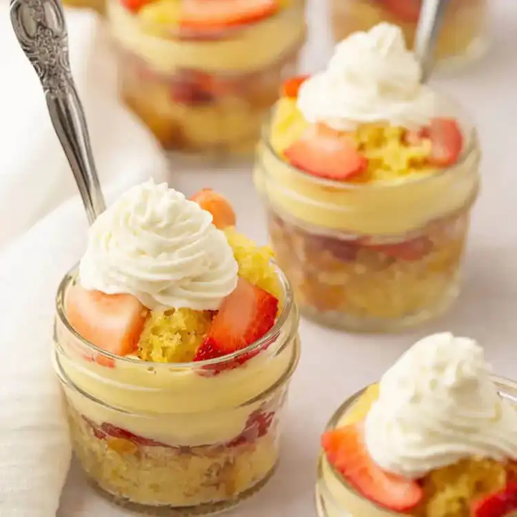 Classic Strawberry Shortcake In A Jar with layers of vanilla cake, fresh sliced strawberries, and whipped cream.