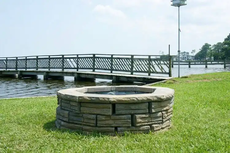 Stylish DIY Retaining Wall Block Fire Pit, featuring textured tan retaining wall blocks forming an elegant circular fire pit.