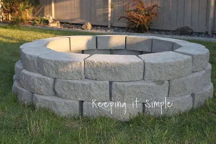 Minimalist $60 DIY Fire Pit made from stacked concrete blocks, set on a unique patterned paver floor, offering an affordable and stylish solution.
