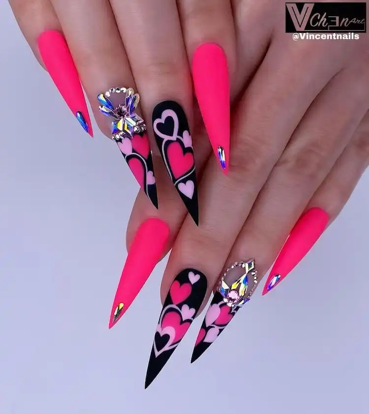 Bold black and pink stiletto acrylic nails with heart designs and rhinestone embellishments, showcasing 16 Extraordinary Pink And Black Nail Design Ideas - French Tip Square Acrylic Nails