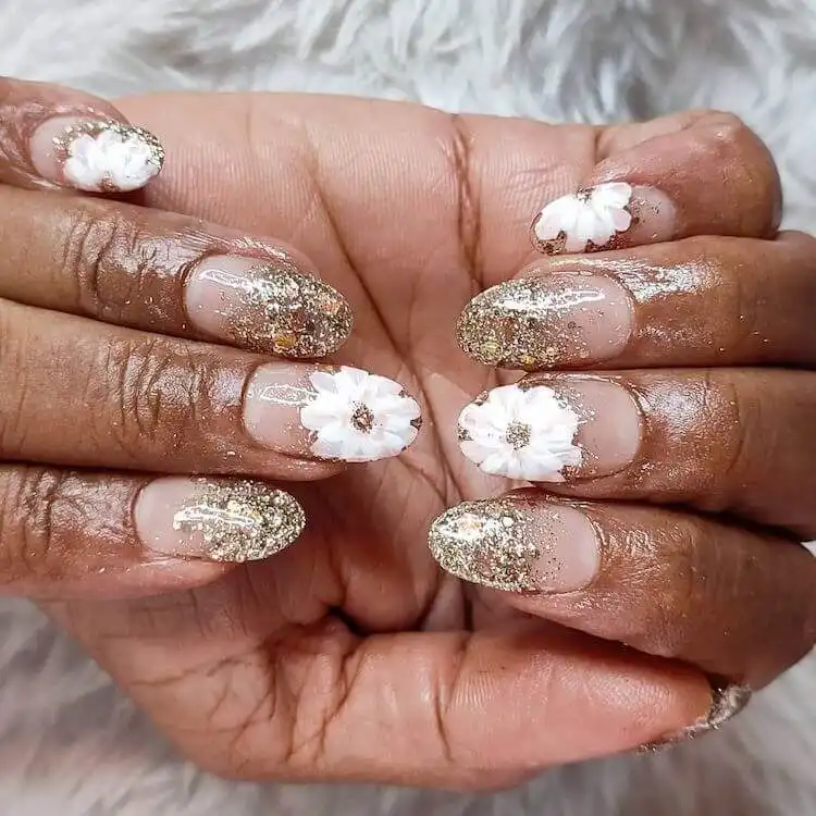 Acrylic nail extensions with a glitter base and delicate hand-painted white flowers.