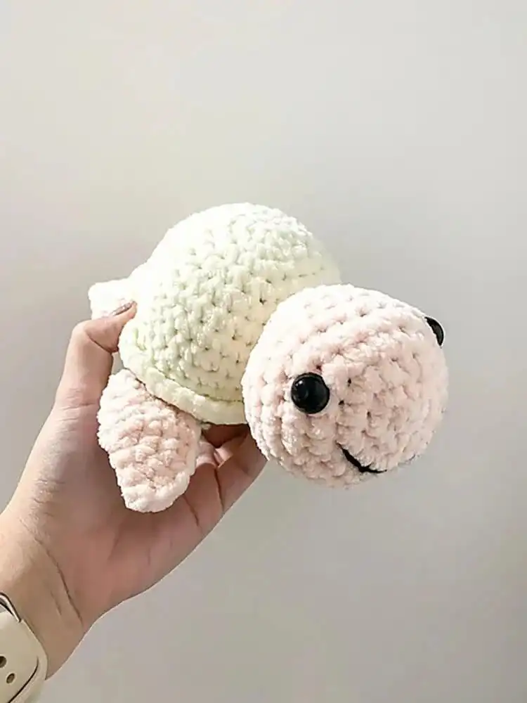 A soft, plush crochet turtle made with chunky chenille yarn in three distinct colors, emphasizing its cuddly texture.
