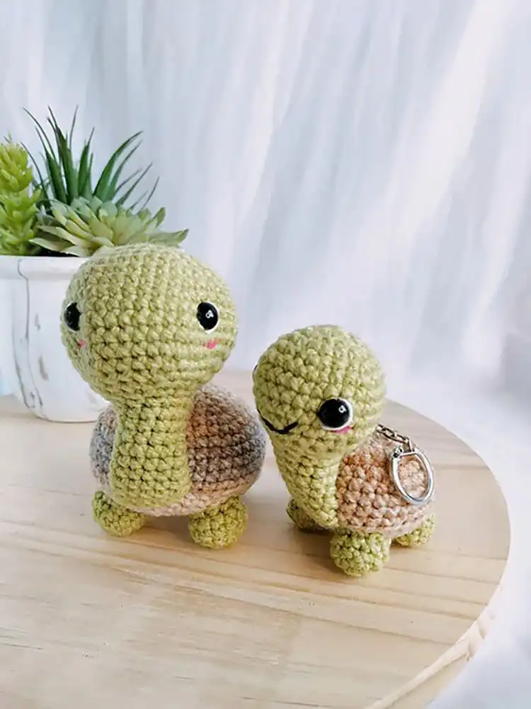 A small, finished crochet turtle attached to a keychain, showcasing a practical and decorative accessory.