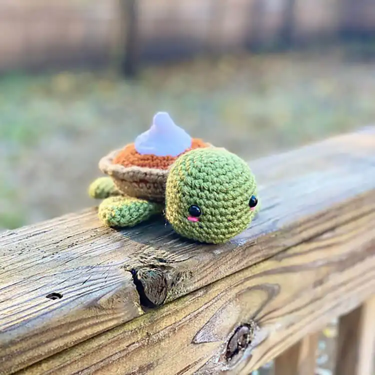 A charming crochet turtle with a shell designed to look like a pumpkin pie, perfect for autumn decor.
