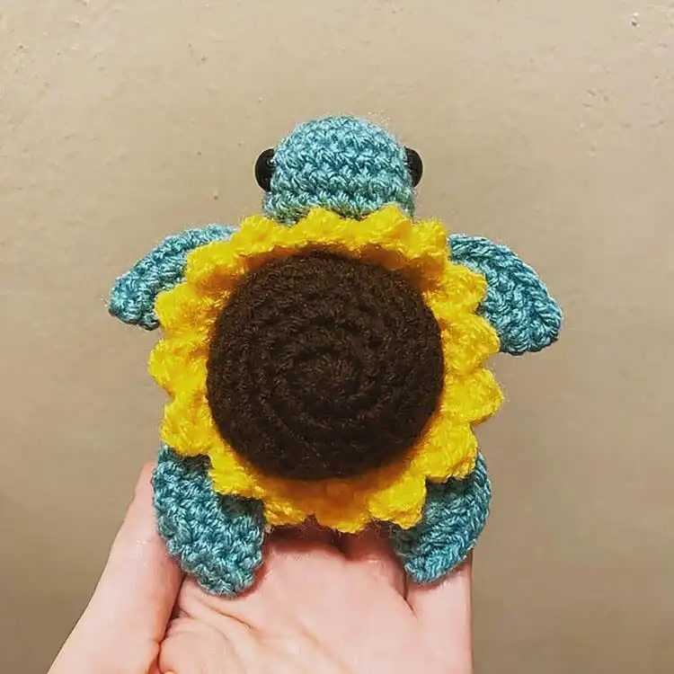 A crochet turtle with a bright yellow sunflower on its back, embodying 'Sunny the Sunflower Turtle' design.