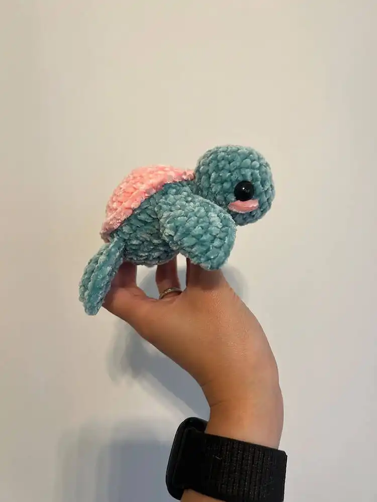 A small, soft mini plushie crochet turtle in pastel colors, designed for cuddles and comfort.