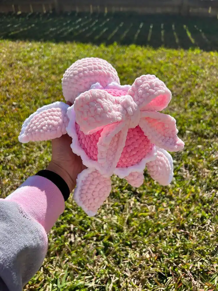 A cute crochet turtle with a decorative bow tied neatly on its back, adding an extra touch of charm.