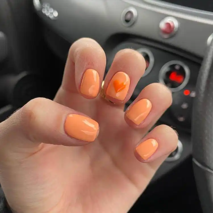 Elegant peach daiquiri and bellini gel nails with hand-painted tiny heart designs, showcasing 18 Simple Orange Nail Designs - Heart Nails.
