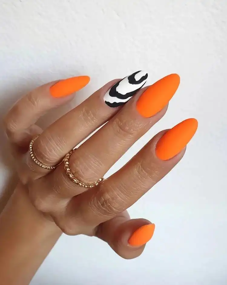 18 Simple Orange Nail Designs - Heart Nails 1 Vibrant matte neon orange nails with a black and white zebra print accent nail, illustrating 18 Simple Orange Nail Designs.