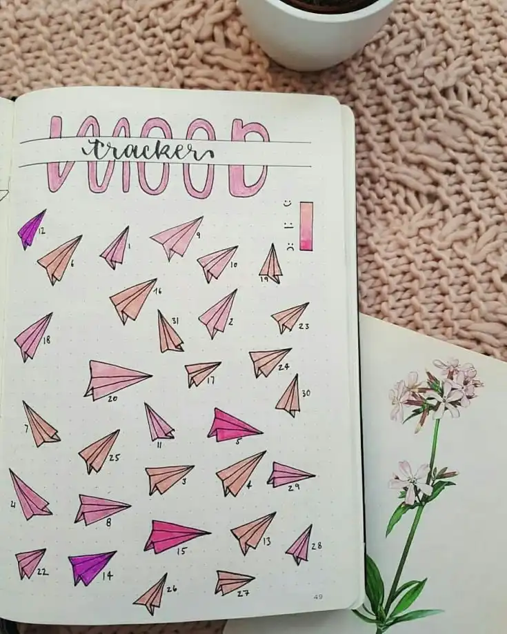 Books and bookshelf mood tracker in a bullet journal, with book spines colored to represent daily moods for readers.
