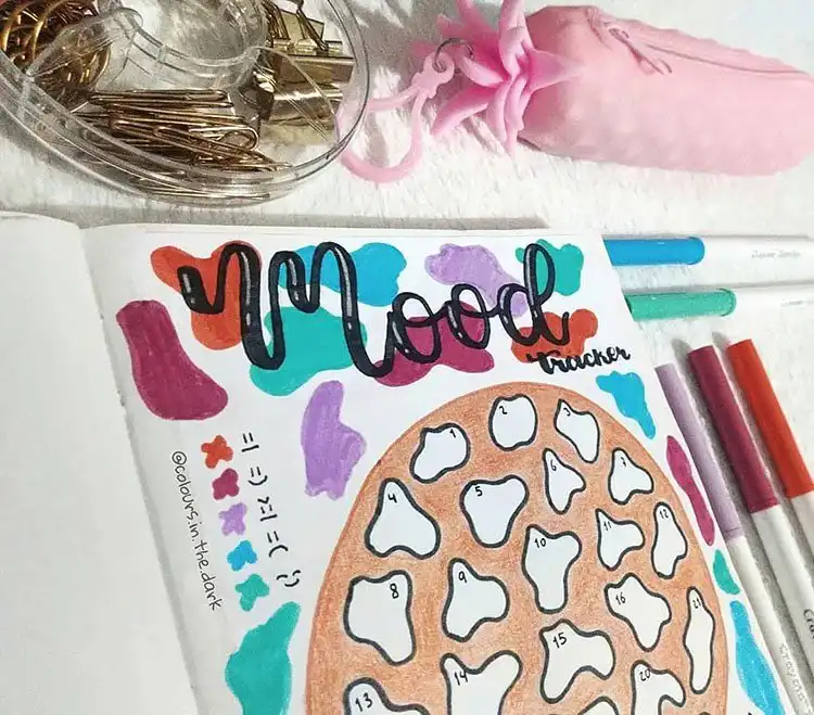 Elegant purple and pink flowers mood tracker in a bullet journal, with daily colored circles representing emotions.