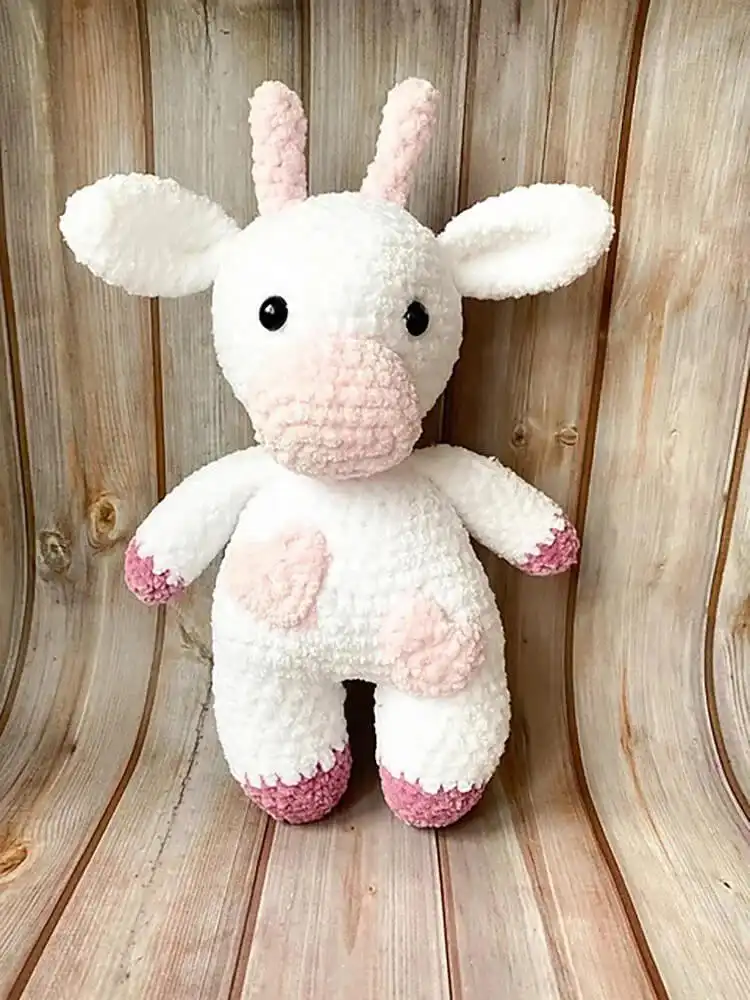 A pair of crochet cows designed as Strawberry and Blueberry Cows, featuring vibrant fruit colors and details.