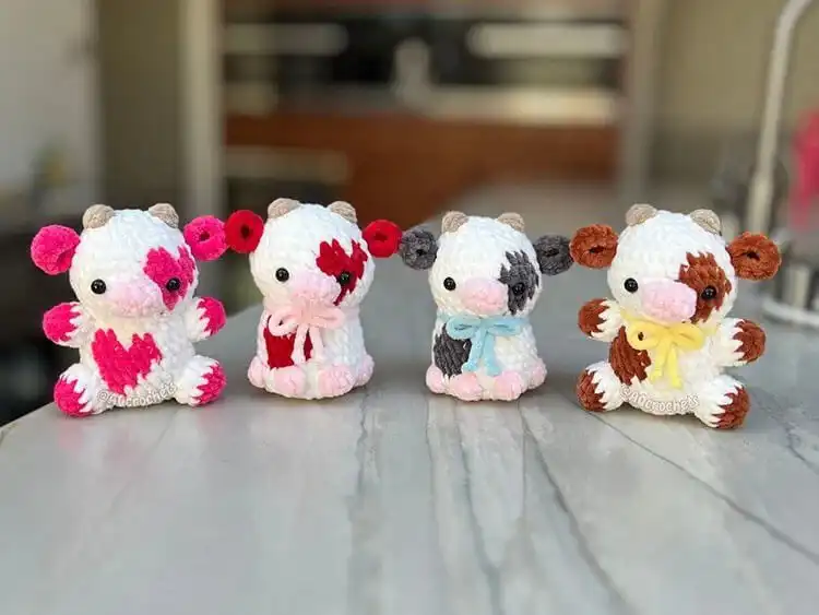 A soft, pink Plush Strawberry Cow crochet plushie, adorned with strawberry-like features and colors.