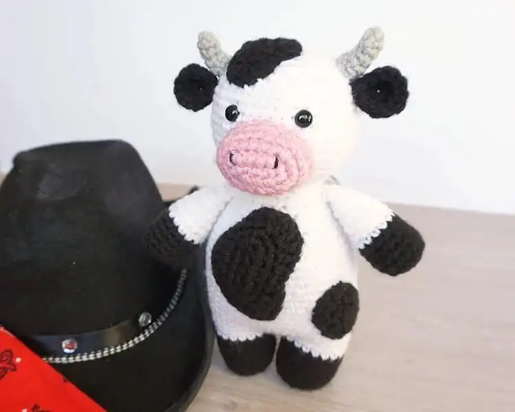 A small, cute black and white crochet Little Cow plushie, perfect for quick and easy projects.