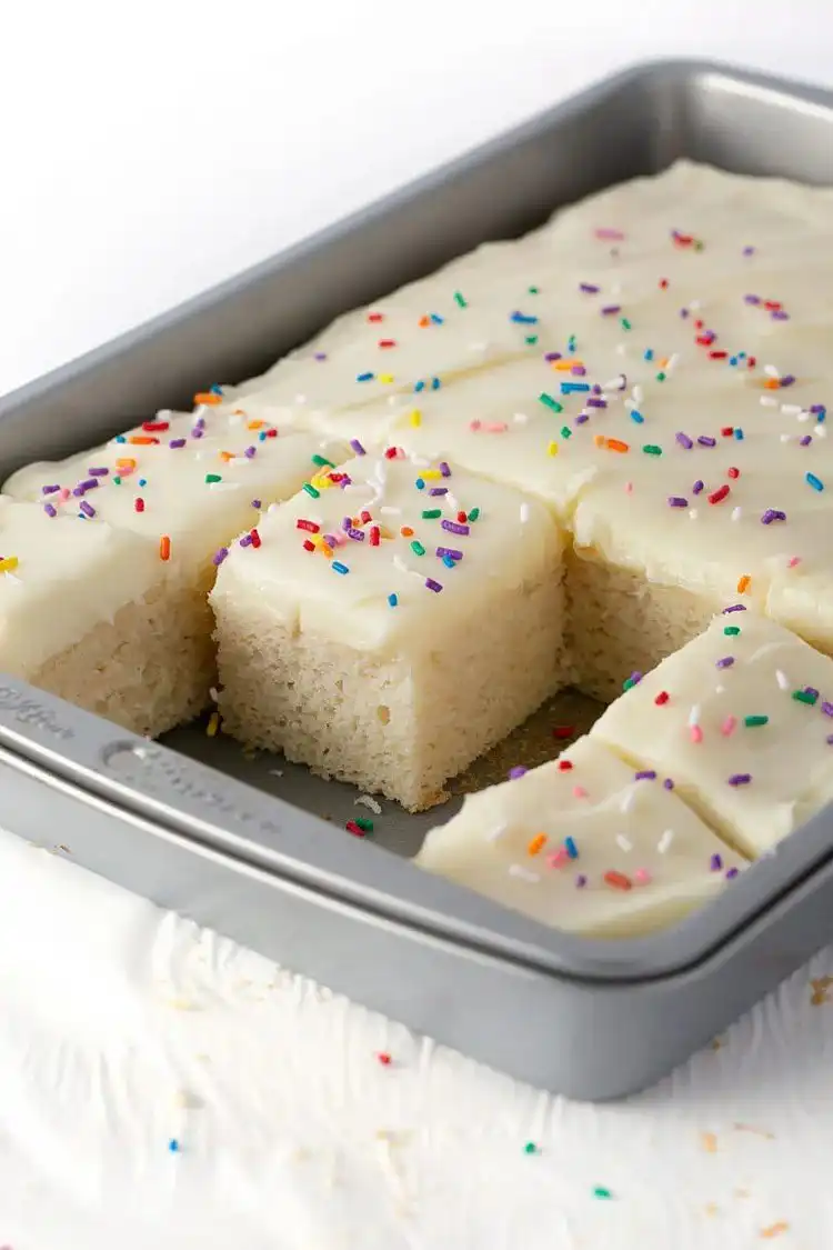 Tall, moist white sheet cake with simple white frosting