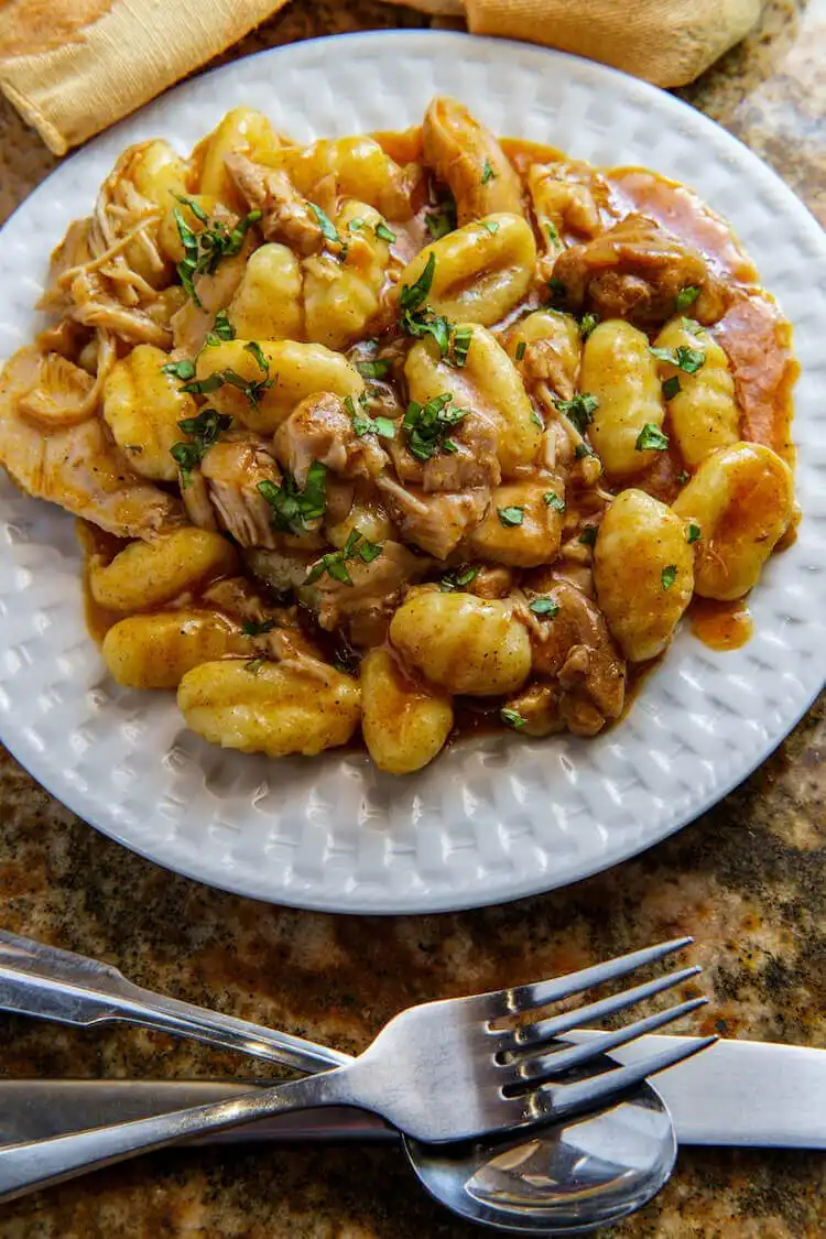 Squirrel confit with duck fat gnocchi, garnished with herbs, a gourmet game meat preparation