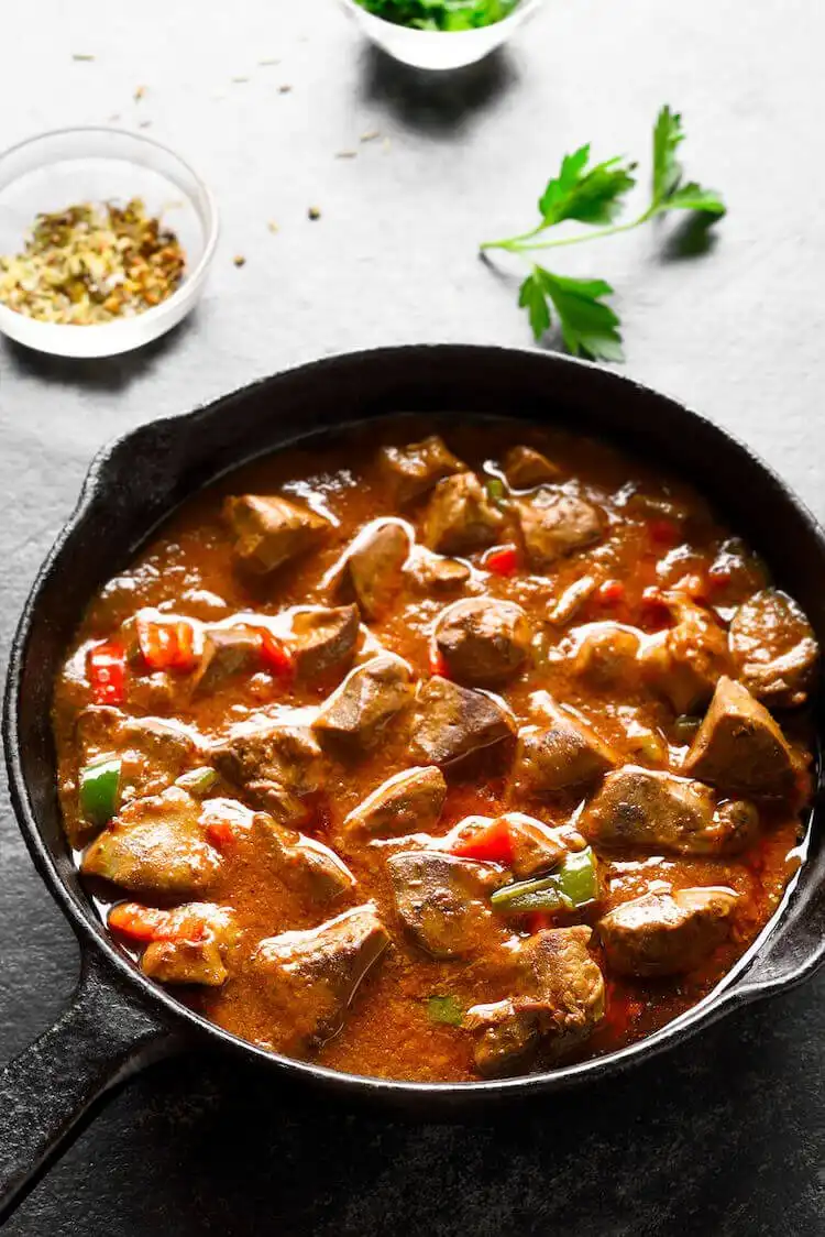 Squirrel stew with paprika and greens in a bowl, vibrant and flavorful, served with mashed potatoes
