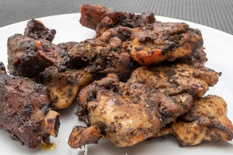 Jerk squirrel pieces on a plate with rice and peas, spicy Jamaican-inspired game meat