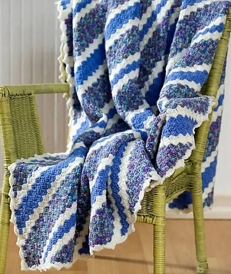 An elegant Corner-to-Corner Guest Throw draped on a bed, showcasing intricate patterns.