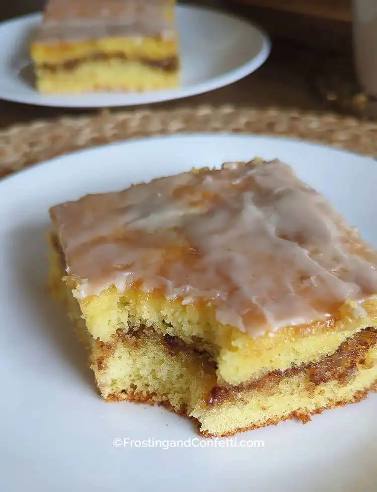 A slice of maple pecan honey bun cake showing the swirled pecan filling and maple glaze.