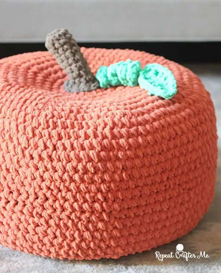 A large, textured crochet pumpkin pouf, suitable as a footrest or accent decor