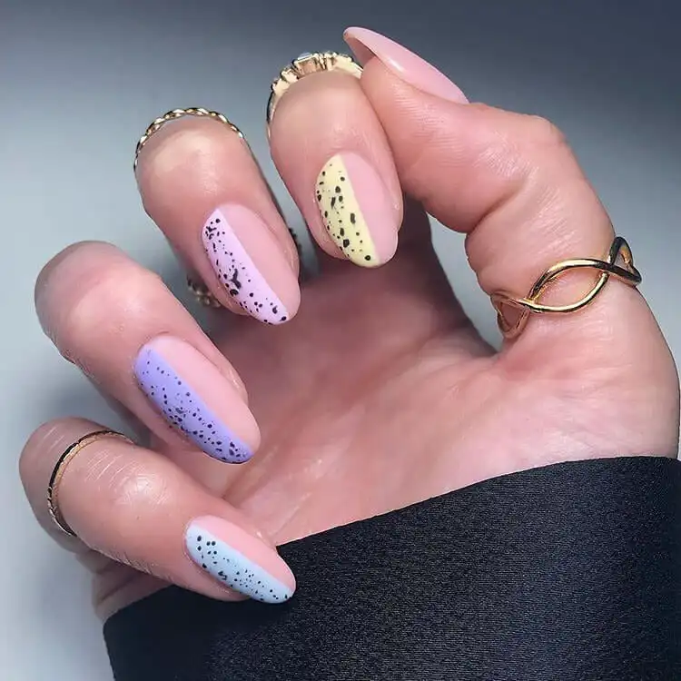 Pastel eggshell-inspired acrylic nails with delicate speckled patterns, perfect for a subtle spring aesthetic.