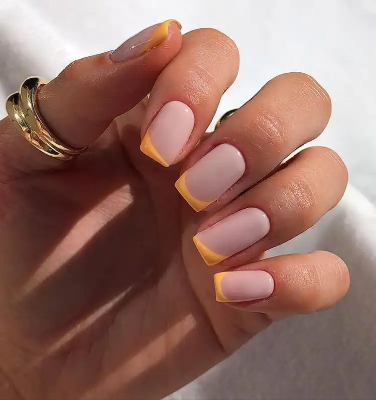 Acrylic nails featuring striking neon orange tips on a clear base, a modern twist on the classic French manicure.