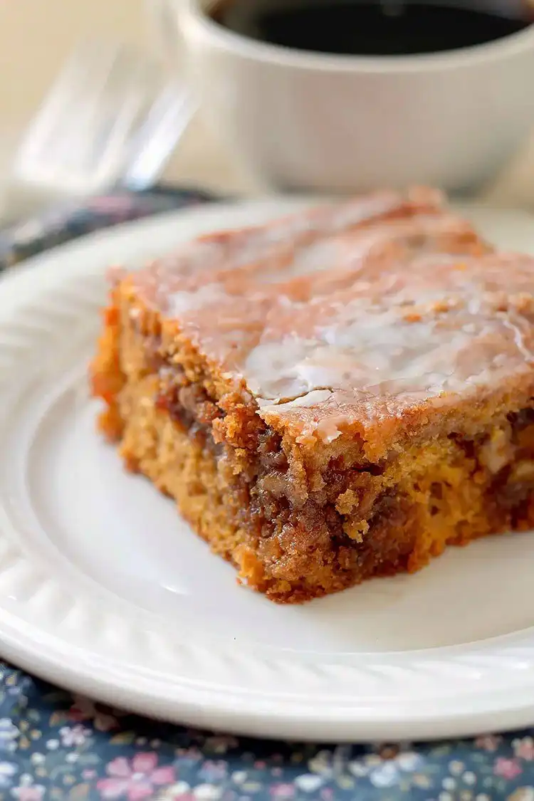 A slice of Pumpkin Honey Bun Cake, showing the swirl of filling and glaze.
