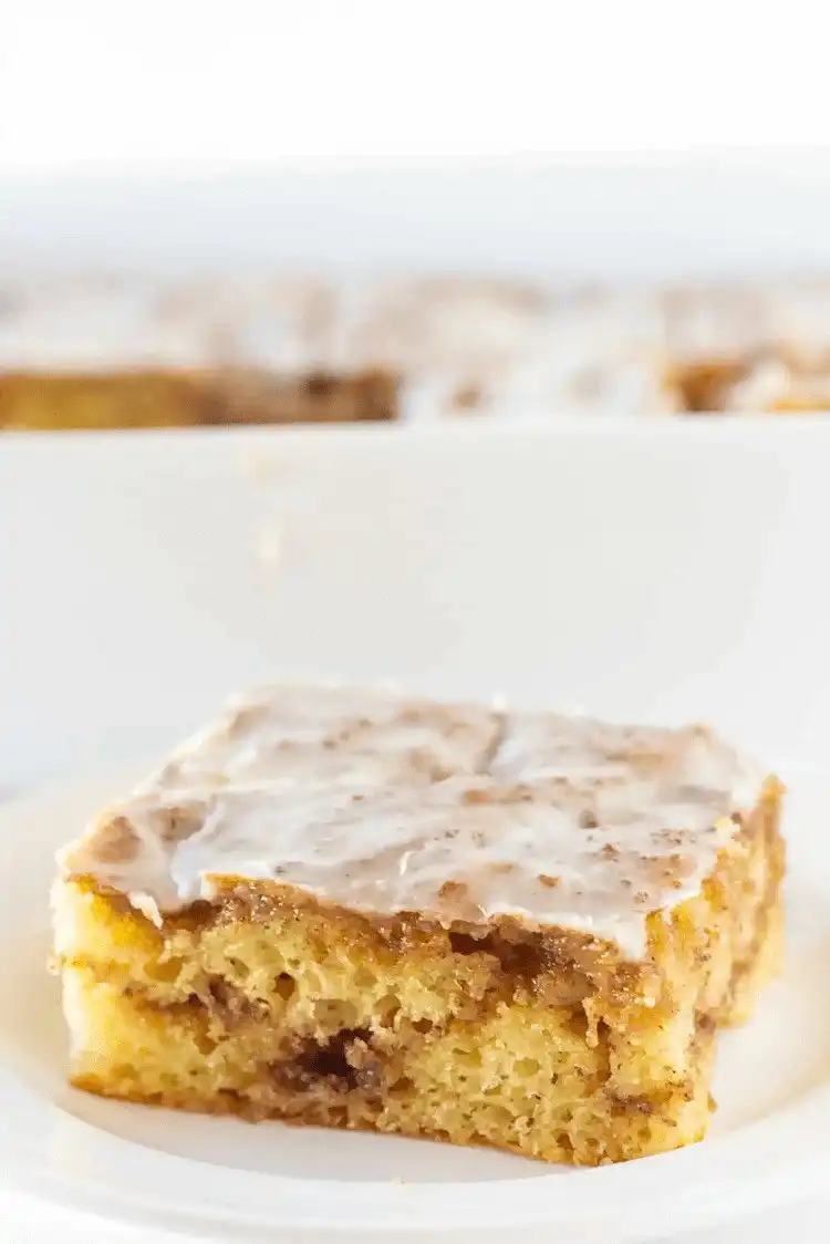 A slice of Easy Cinnamon Roll Cake with visible cinnamon swirl and icing.