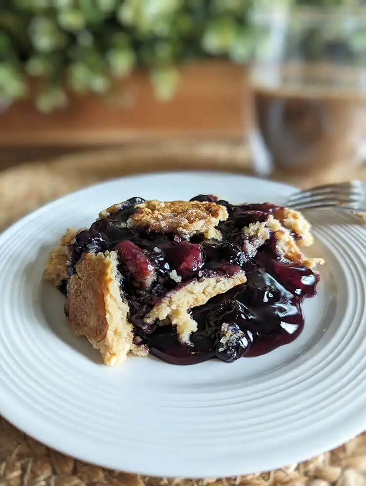 A warm 3-Ingredient Blueberry Dump Cake in a baking dish, bubbling with blueberries.