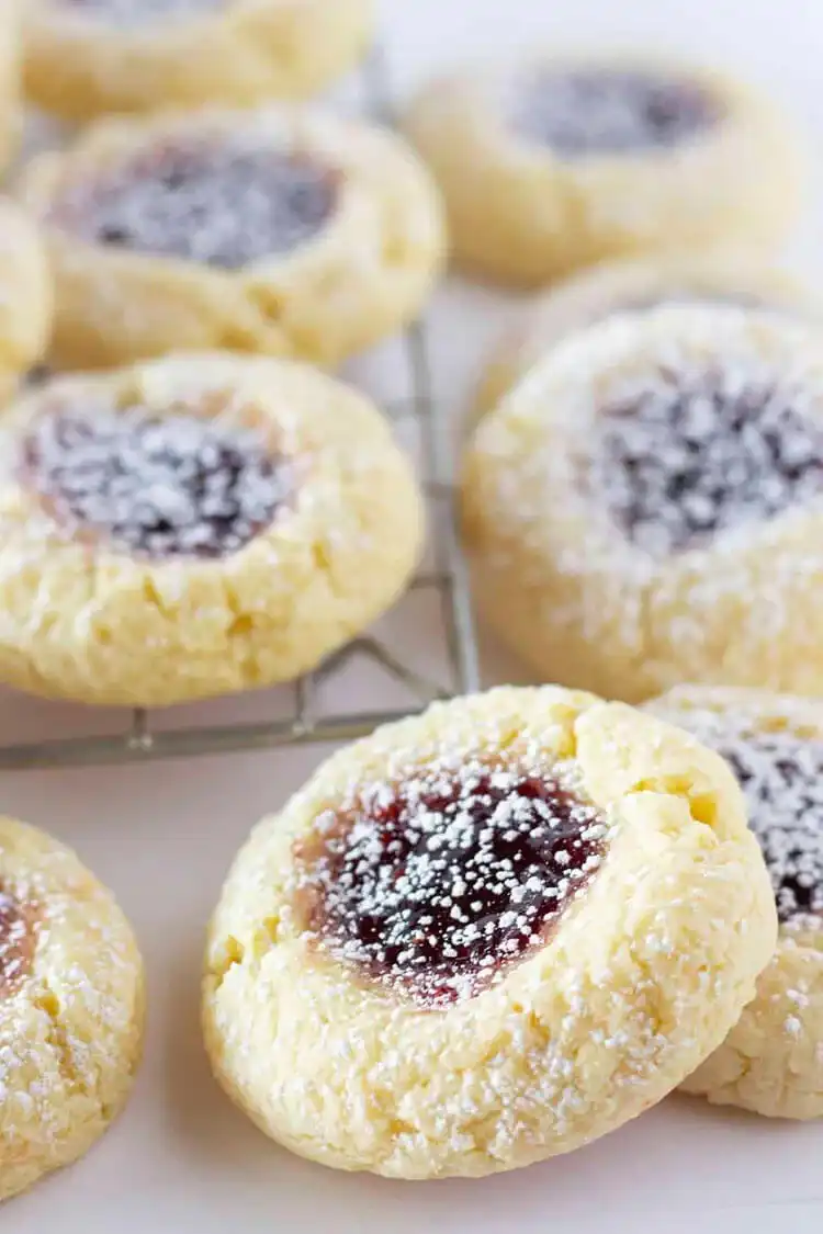 Yellow Cake Mix Thumbprint Cookies filled with bright red jam on a cooling rack.