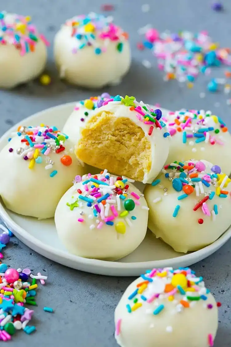 Assorted Cake Balls decorated with drizzles and sprinkles, arranged on a plate.