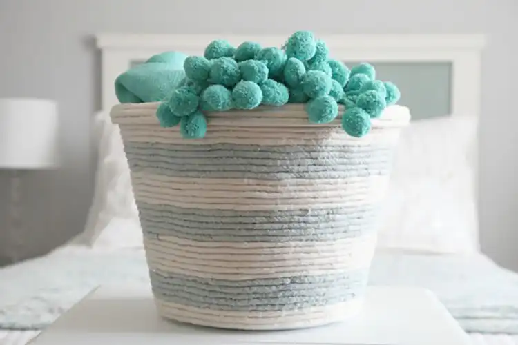 A plain plastic dollar store basket completely covered with wrapped rope, transforming it into a chic storage container.