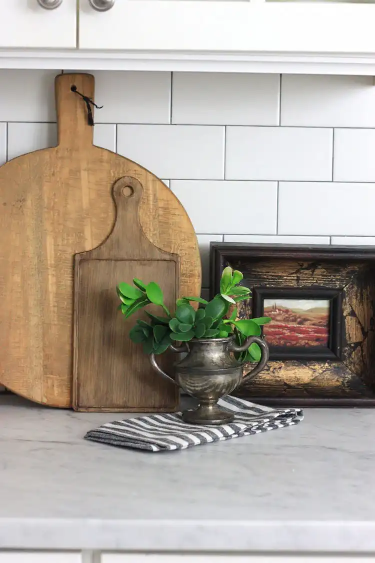 A plastic dollar store cutting board transformed with paint and stain to resemble an antique wooden board, displayed in a kitchen.