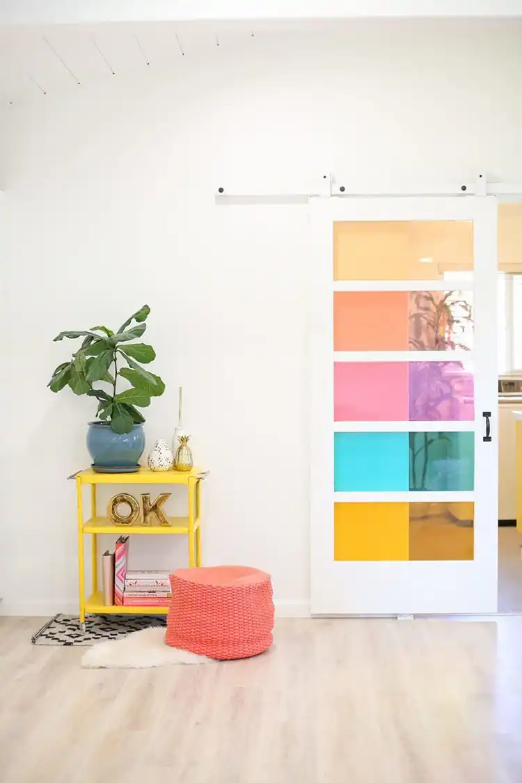 A window pane decorated with colorful translucent film, creating a faux stained glass effect with geometric patterns.