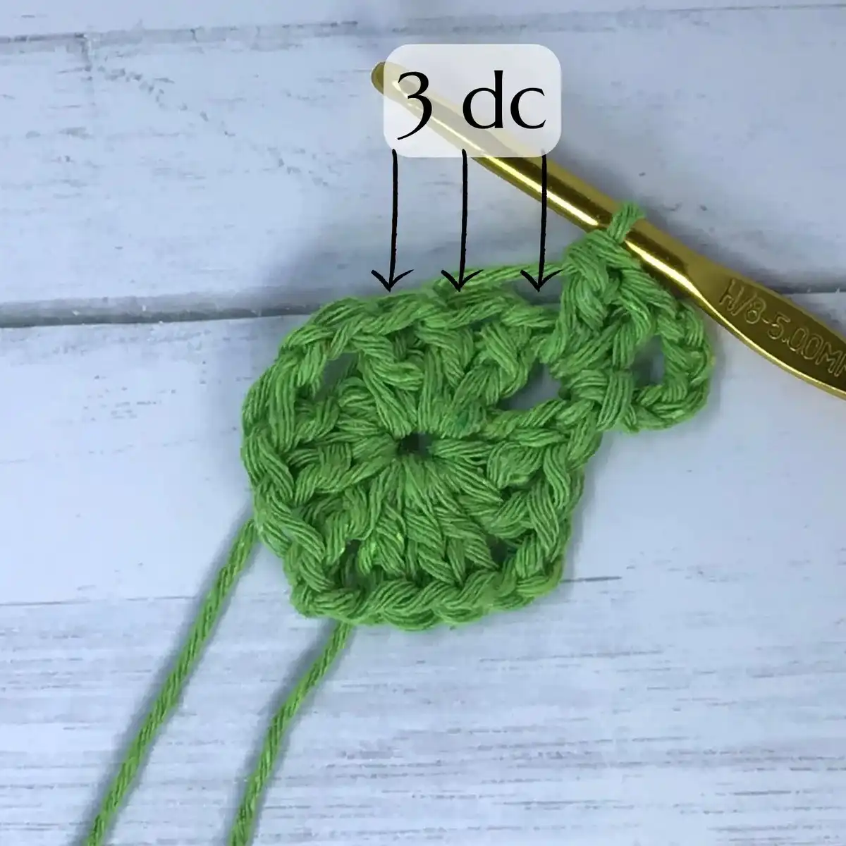 Detailed photo showing the completion of round one for how to crochet a solid granny square, with stitches forming the initial square shape.