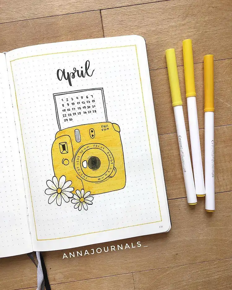 An Instax camera frame April bullet journal cover page, with a central space for the month and surrounding floral doodles.