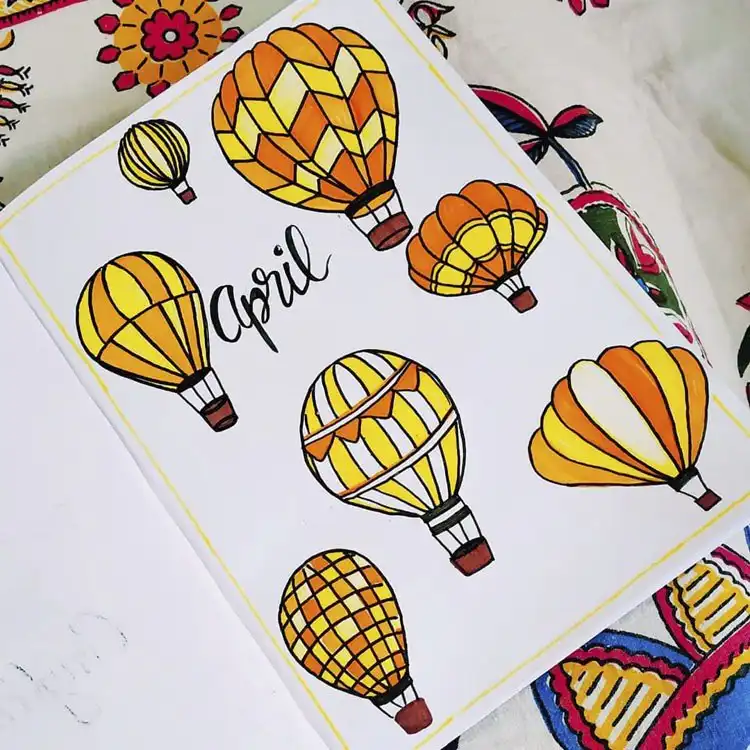 An April bullet journal cover page featuring vibrant yellow and orange hot air balloons standing out brightly.