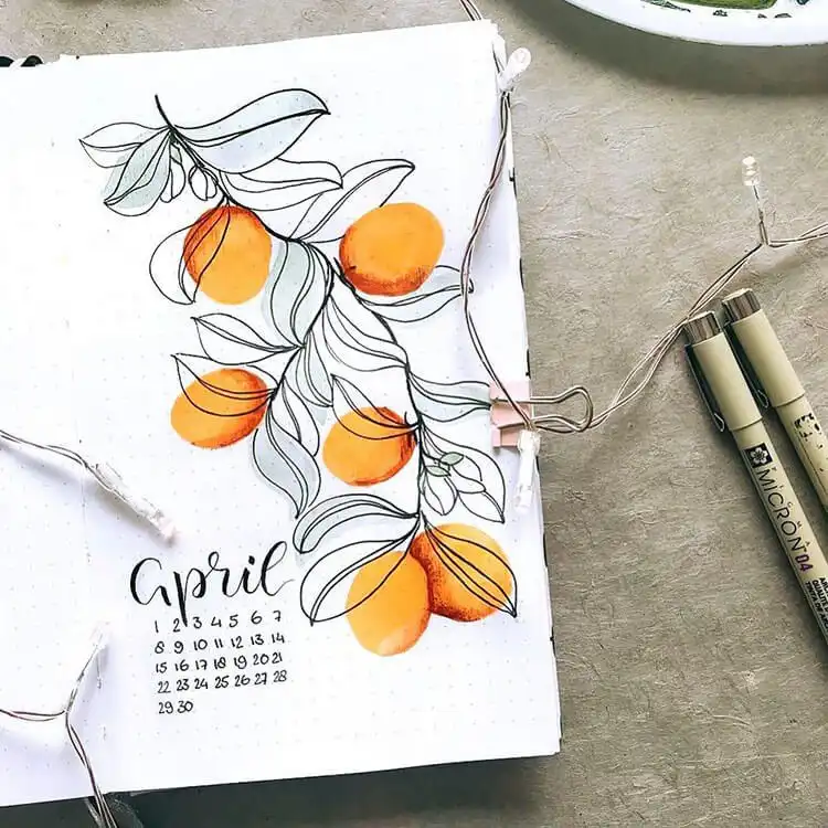 An April bullet journal cover page featuring cheerful oranges and green leaves, creating a fresh and zesty spring look.