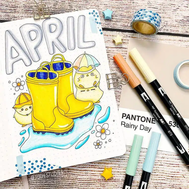 A whimsical April bullet journal cover page showing yellow rain boots, tiny chicks, and gentle raindrops.