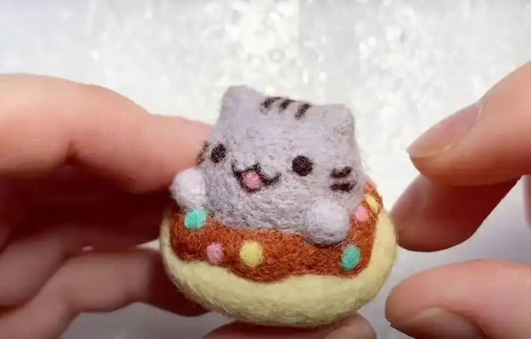 Best Needle Felting Ideas, Kits, and DIY Tutorials 2 Needle felted Pusheen cat character shaped like a donut, showing soft wool texture and colorful details