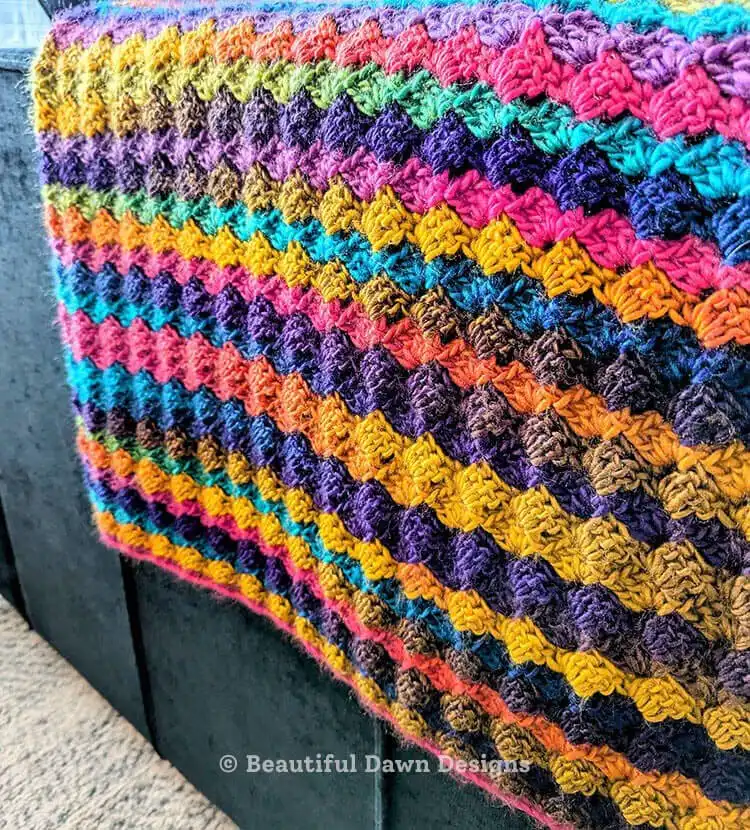 Finished Blooming Hues Crochet Blanket Pattern neatly folded, displaying its full size and the uniform, soft texture created by the one-row repeat.