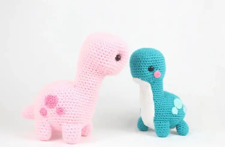 Cute green crochet Brontosaurus amigurumi with a long neck and tail, standing on a light background, showcasing the plush dino design.